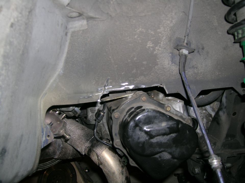 Undercarriage view of a car's transmission and exhaust manifold, with heat wrap on the manifold