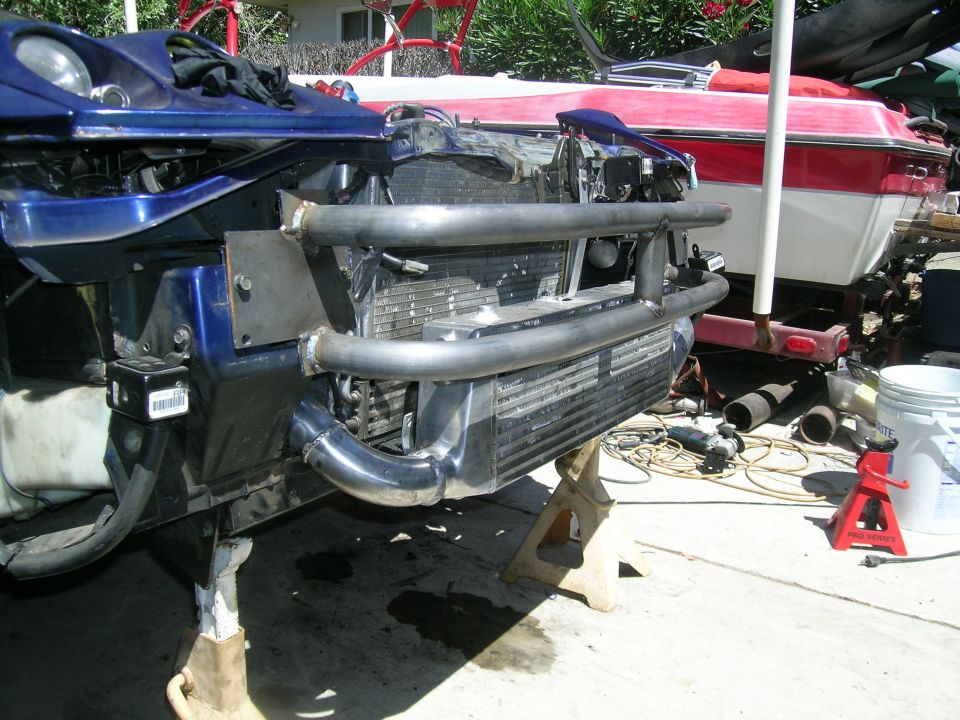 Blue 1995 Ford Probe front end on jack stands, showing custom intercooler and piping