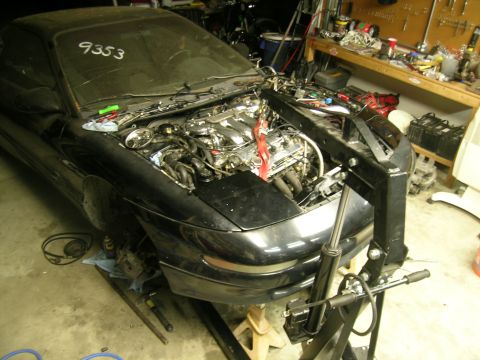 1995 Ford Probe - A black coupe is in a garage with its engine removed and the hood open, supported by jack stands.