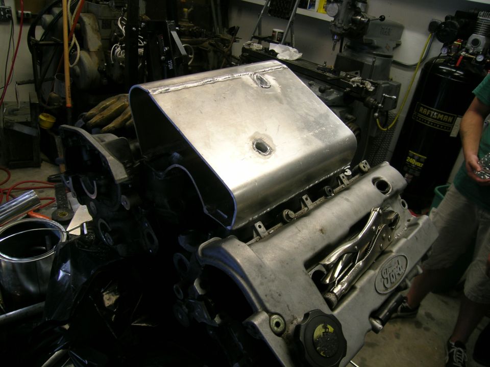 Ford engine with a custom aluminum intake manifold installed, showing a "Ford" logo on the valve cover