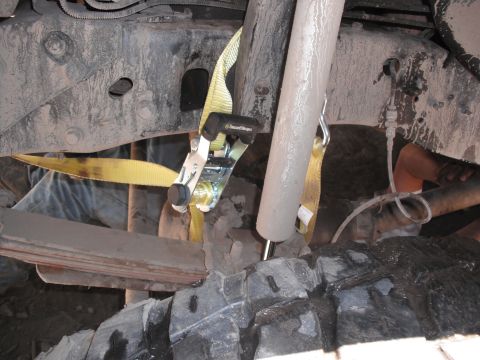 1991 Ford Bronco - A close-up view of the suspension system and a tie-down strap on a vehicle's undercarriage.