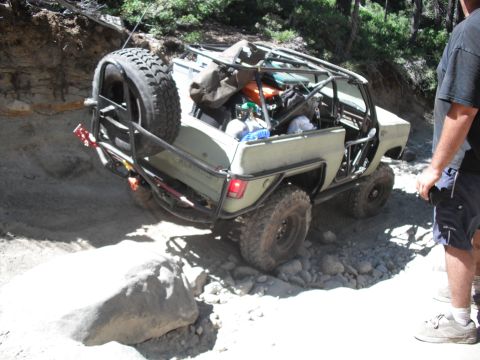 1991 Ford Bronco - Off-road vehicle navigating a rocky trail with a spare tire mounted at the rear.