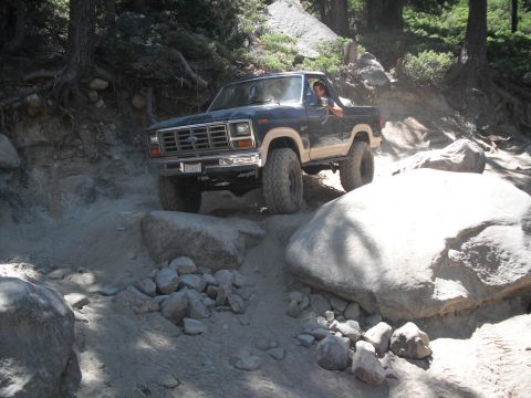 1991 Ford Bronco - A 1979 Ford F-150 navigates a challenging off-road path with large boulders.