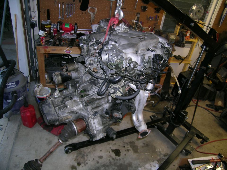 Engine assembly on hoist, V6 engine cover visible