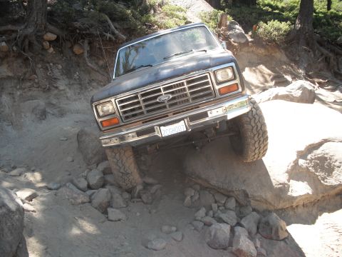 1991 Ford Bronco - This Ford Bronco navigates a challenging rocky trail, demonstrating its off-road capabilities. The front grille and headlights suggest an e…