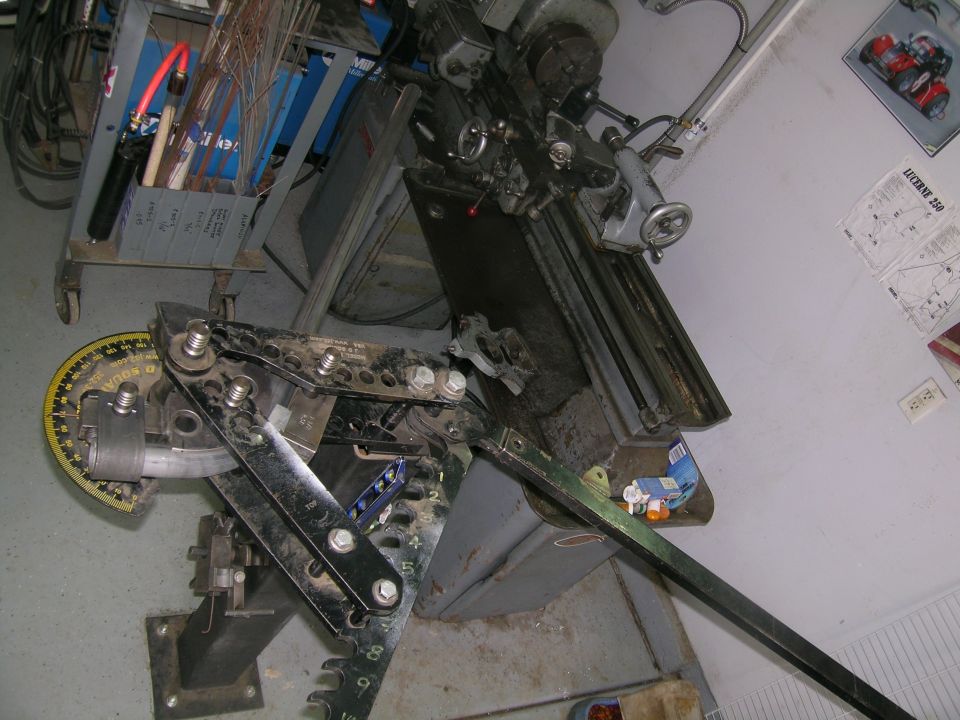 Metal pipe bender with degree markings and a lathe in a workshop setting