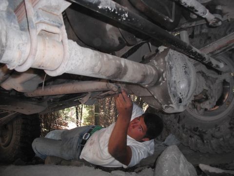1991 Ford Bronco - A person works on the rear axle and suspension components of a large vehicle.