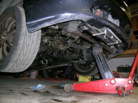 1995 Ford Probe - Undercarriage view of a vehicle being worked on, showing the engine and suspension components.