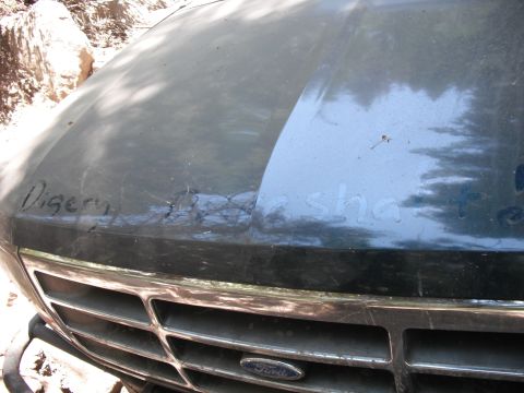 1991 Ford Bronco - The front of a dark green Ford truck, a chrome grille and handwritten text on the hood.