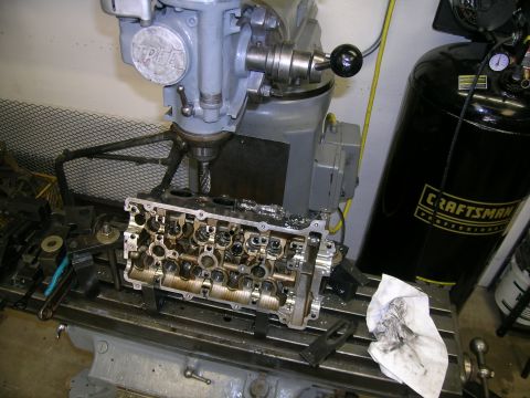1995 Ford Probe - Engine cylinder head being worked on by a milling machine, with a Craftsman air compressor visible.