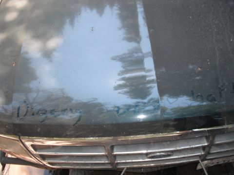 1991 Ford Bronco - Handwritten text is visible on the hood of a dark green vehicle, with a chrome grille below.