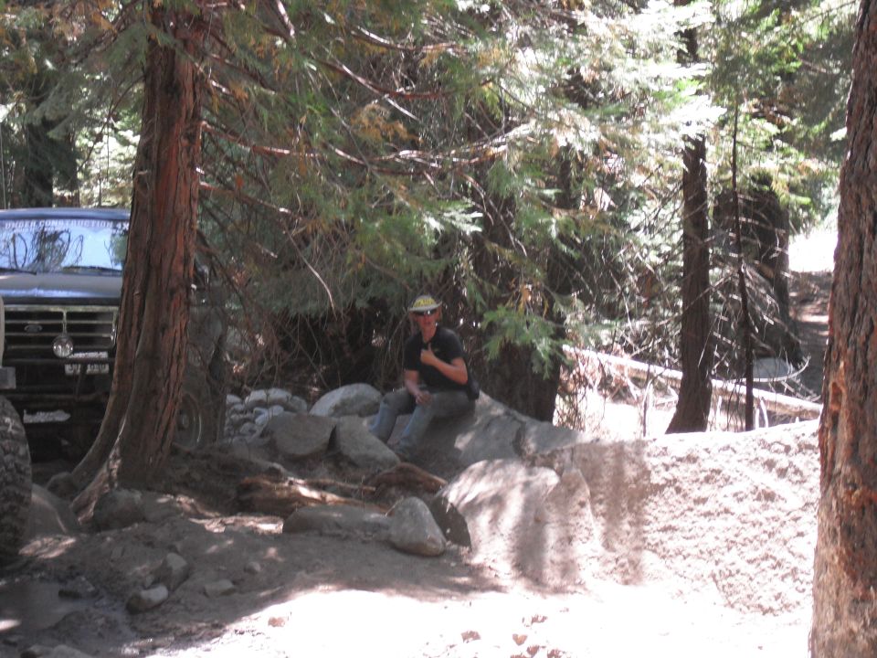1991 Ford Bronco parked on a dirt trail with trees and rocks