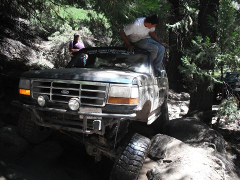 1991 Ford Bronco - A Ford truck with "Under Construction" sticker on windshield navigates a challenging off-road course.