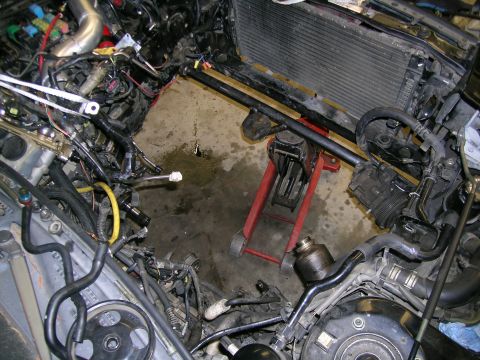 1995 Ford Probe - The engine bay is partially disassembled, with a car jack in place and numerous hoses and wires visible.