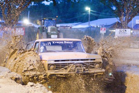 2005 Ford Excursion - Mud bogging event with a classic Ford F-Series truck and a tractor in the background.