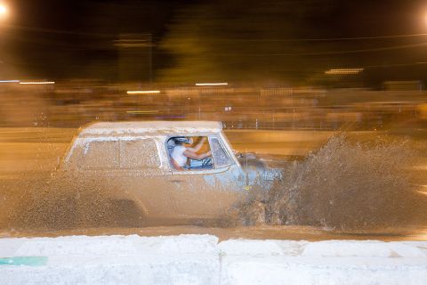 2005 Ford Excursion - A vehicle navigates a muddy track, sending up a large spray of water and mud.