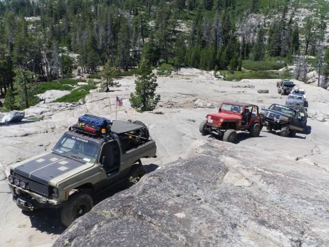 1991 Ford Bronco - A convoy of off-road vehicles navigates a challenging rocky landscape under a clear sky.