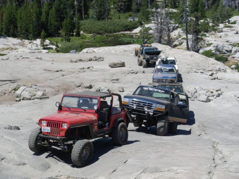 1991 Ford Bronco - A line of off-road vehicles navigates a rocky trail, with a 1992 Ford F-150 pickup truck in the foreground.