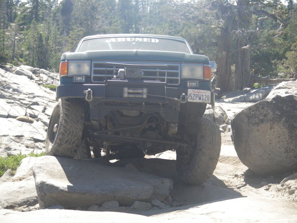 Ford F-Series truck on rocks, windshield sticker says 'ABUSED', California plate 5ZPW128