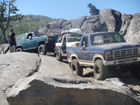 1991 Ford Bronco - Multiple 4x4 vehicles navigate a challenging rocky terrain on a sunny day.