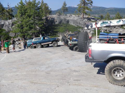 1991 Ford Bronco - A group of people stand near a lifted Ford Bronco on a rocky, off-road trail.