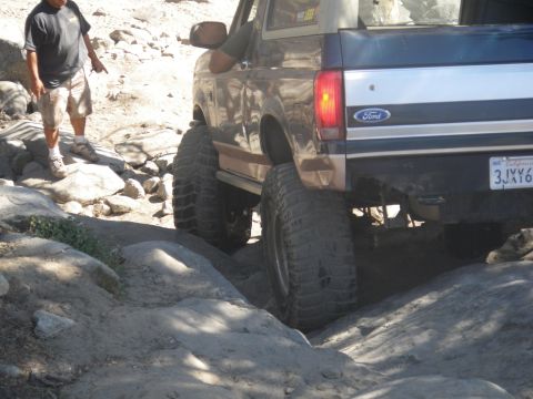 1991 Ford Bronco - 1991 Ford Bronco rear view on a rocky trail. The vehicle has been lifted and fitted with large off-road tires.