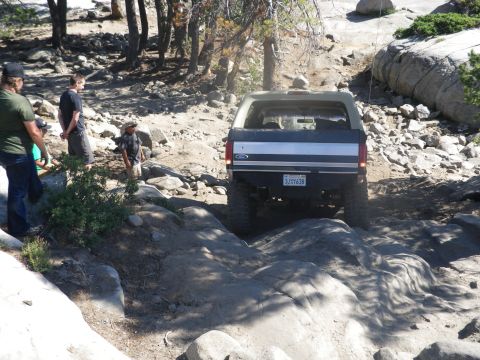 1991 Ford Bronco - This Ford Bronco navigates a challenging rocky terrain, showing its rear profile and off-road capabilities.