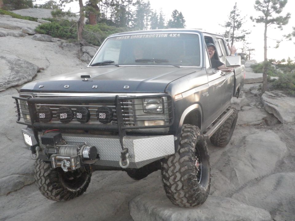 Gray Ford Bronco off-roading on rocks, with a winch and brush guard