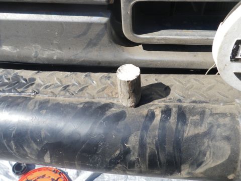1991 Ford Bronco - A wooden block rests on the textured surface of a vehicle's bumper.