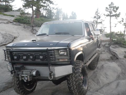 1991 Ford Bronco - This modified Ford F-Series truck navigates a rocky trail with its aggressive off-road tires and custom front bumper.