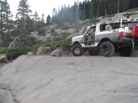 1991 Ford Bronco - This modified 1991 Ford Bronco is shown off-road with its doors removed, navigating a rocky landscape.