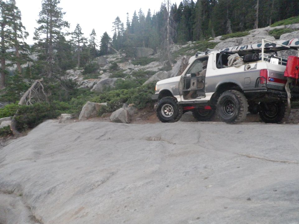 1991 Ford Bronco off-road with doors removed, parked on rocky terrain