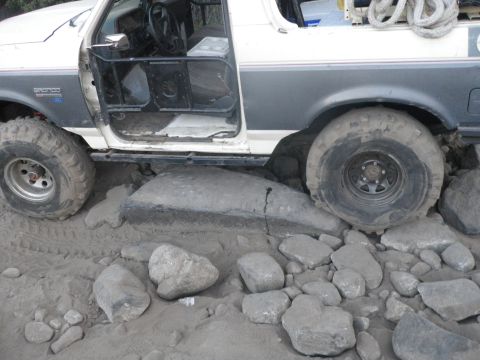 1991 Ford Bronco - This 1991 Ford Bronco is navigating a rocky, sandy terrain with its driver's door open.