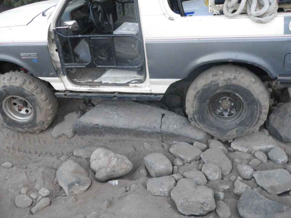 1991 Ford Bronco with door open, tires on rocks and sand