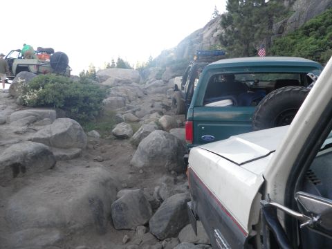 1991 Ford Bronco - Several off-road vehicles, including a 1991 Ford Bronco, are seen on a challenging rocky trail.