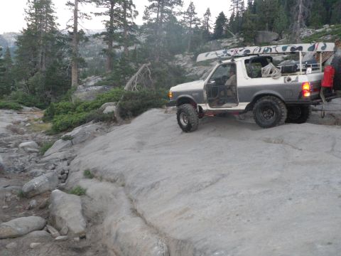 1991 Ford Bronco - A 1991 Ford Bronco navigates a rocky trail with a canoe strapped to its roof.