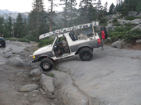 1991 Ford Bronco - Off-road adventure with a 1991 Ford Bronco carrying a canoe over challenging rocky trails.