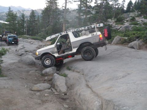 1991 Ford Bronco - A modified 1991 Ford Bronco tackles a challenging rocky terrain, equipped for an outdoor adventure.