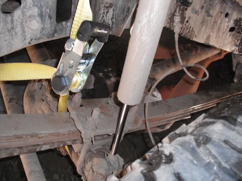 1991 Ford Bronco - Close-up view of a yellow tie-down strap secured to the suspension system of a vehicle.