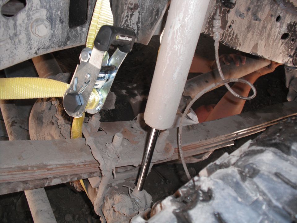 Tie-down strap attached to vehicle suspension components