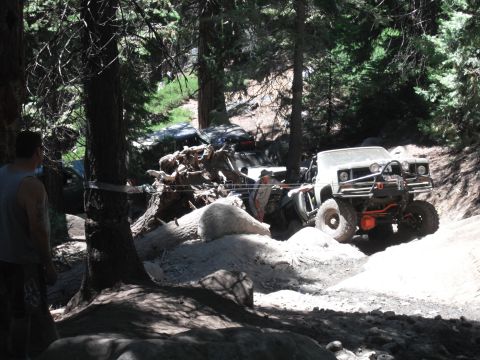 1991 Ford Bronco - This heavily modified off-road vehicle is navigating a challenging trail with debris and other vehicles present.
