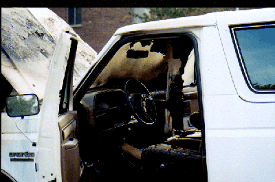 1989 Ford Bronco - Interior view of a white SUV with the driver's door ajar.