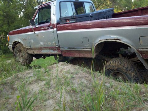 1988 Ford F-150 - This pickup truck appears to be from the late 1980s, possibly a 1987 model, and is stuck in a muddy area.