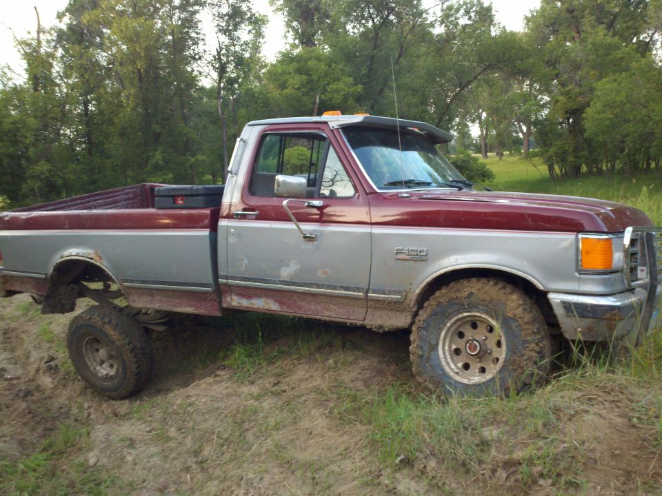 Red and silver 1988 Ford F-150 pickup truck parked off-road