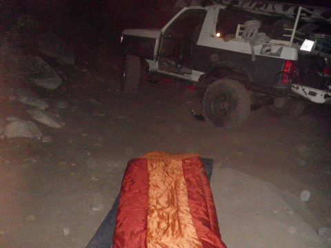 1991 Ford Bronco - A two-tone Ford Bronco is parked on a dirt road at night, with its driver's door open.