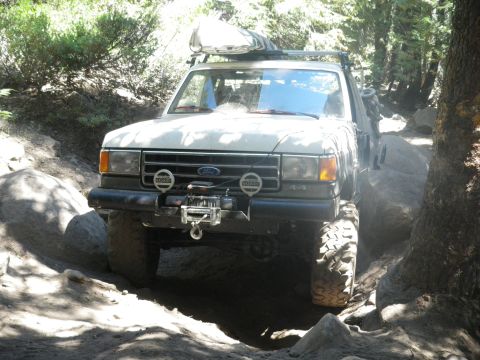 1991 Ford Bronco - This 1991 Ford Bronco navigates a challenging rocky path, equipped with a winch and a roof rack for adventure.