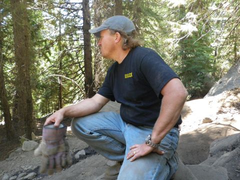 1991 Ford Bronco - Man in a wooded area holds a work glove while looking off to the side.