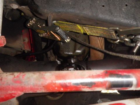 1991 Ford Bronco - Undercarriage view of a vehicle, focusing on a strap and clamp securing a part.