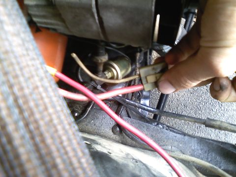 1990 Ford Bronco - A hand connects a wire to the starter solenoid, part of the engine's electrical system.