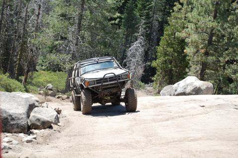 1993 Jeep Wrangler - This heavily modified Toyota 4Runner navigates a rocky off-road trail surrounded by dense forest.